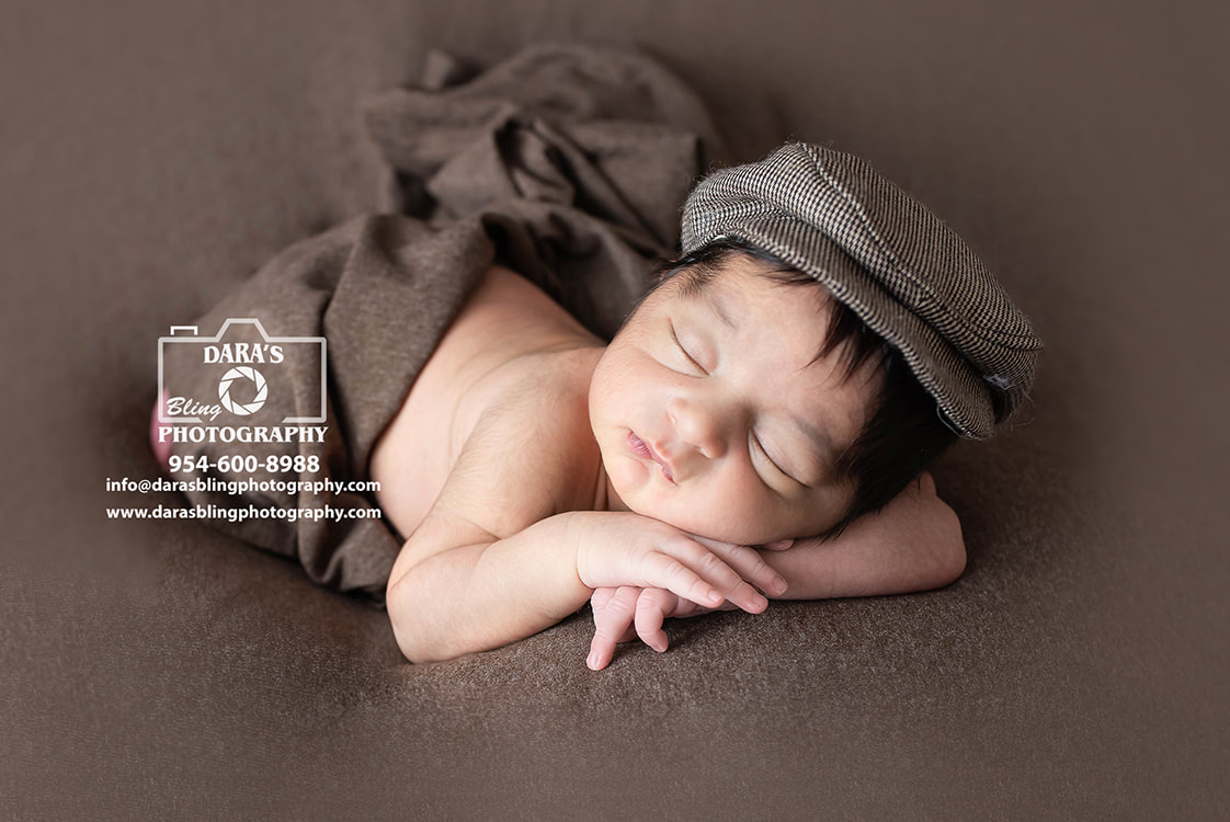 newborn baby boy posed on bed with brown
