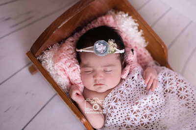 Tamarac newborn photographer newborn girl in bed with pink and white