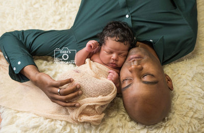 Military dad newborn photography session lying on fur with baby